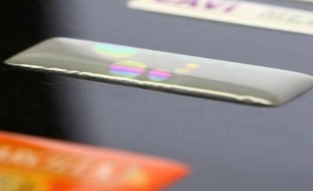 Etiqueta serigrafiada con acabado brillante y efecto holográfico sobre una superficie negra