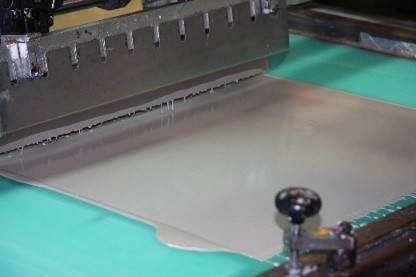 Máquina de serigrafía industrial aplicando tinta sobre una superficie en el proceso de impresión